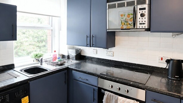 Une cuisine compacte équipée d’un lave-linge, d’un four à micro-ondes et d’un four traditionnel.