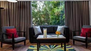 A modern living room with a black sofa, two armchairs, a coffee table, and a large window with curtains. - Collection O Thrissur Zoo & Museum (Thrissur)