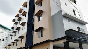 A multi-story building with a modern architectural design, featuring a series of balconies with awnings and a prominent vertical blue glass facade. - Collection O Thrissur Zoo & Museum (Thrissur)