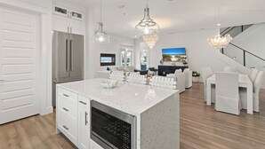 A modern kitchen with white cabinetry, stainless steel appliances, and a central island. - Golf Cart Perks, Large Private Pool, Close to Beach (Santa Rosa Beach)