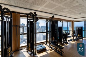 A gym with various exercise equipment, large windows, and a view of the city. - Enjoy sea view from 11th floor 200m from the sea (Salvador)
