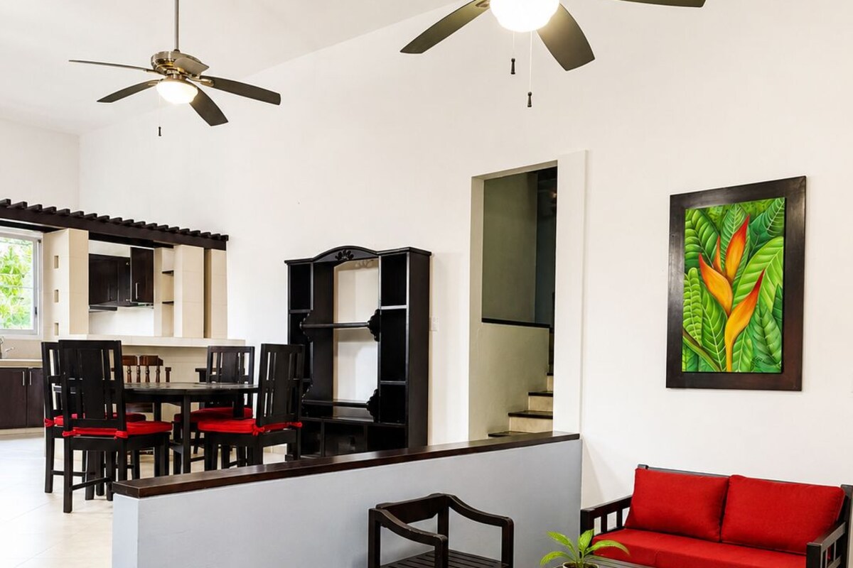 A modern living space with a dining area, a sofa, and a ceiling fan.