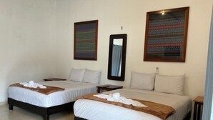 Habitación de hotel con dos camas, una mesita de noche, un espejo y dos obras de arte enmarcadas en la pared.