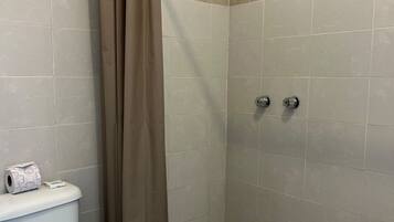 Baño con inodoro, ducha y baldosas de suelo estampadas.