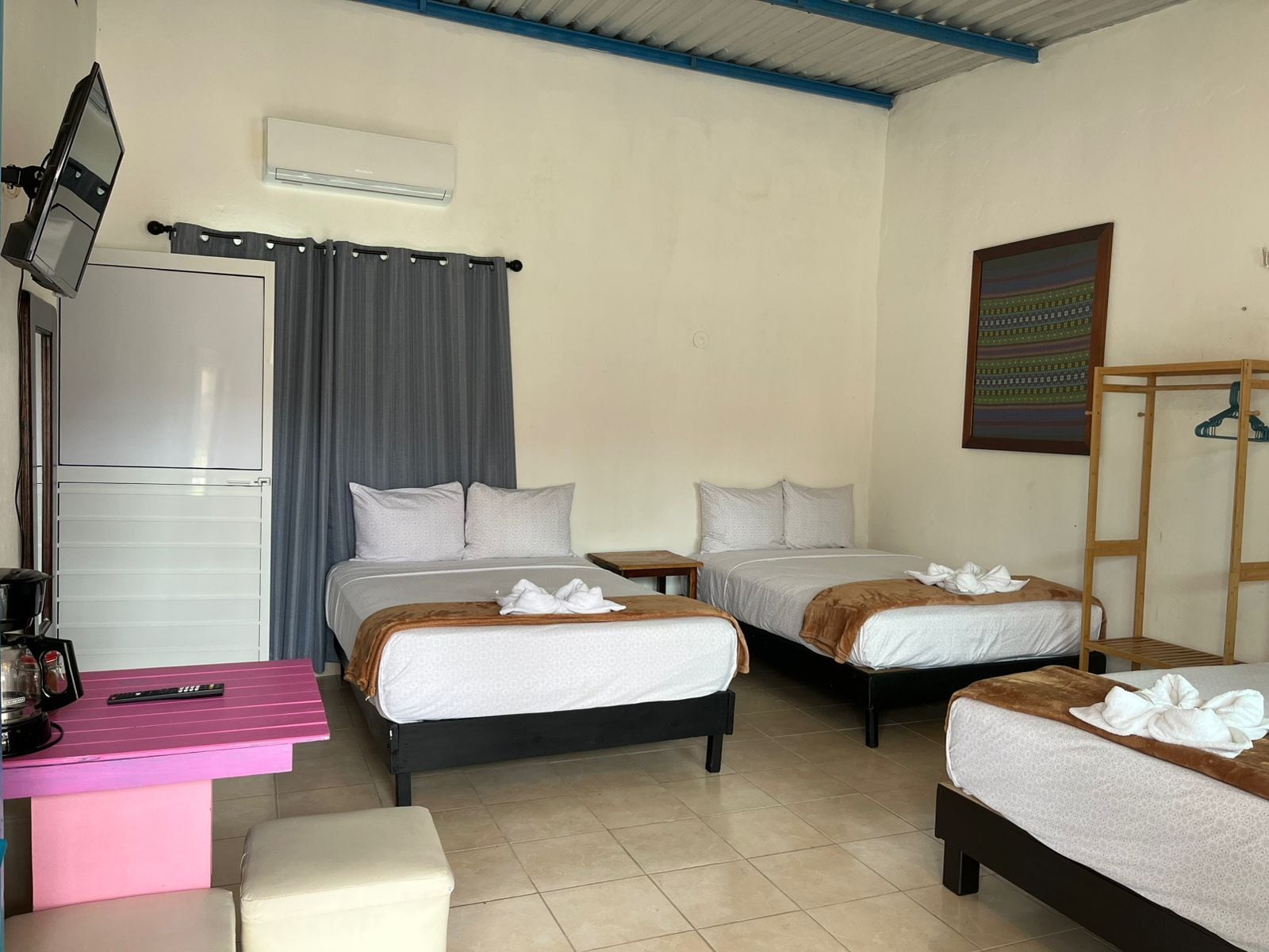 A hotel room with two beds, a desk with a computer, a television, and a wardrobe.