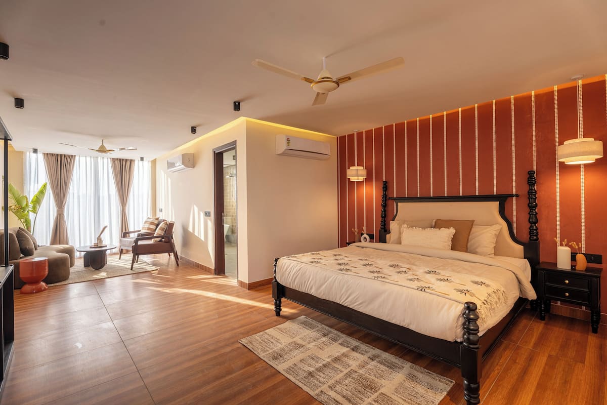A bedroom with a large bed, a ceiling fan, a nightstand, and a wall-mounted air conditioner.