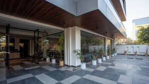 A modern building with a checkered floor, glass doors, and potted plants. - The Hi-rise (Gurugram)