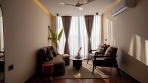 A modern living room with a ceiling fan, a sofa, a chair, and a coffee table. - The Hi-rise (Gurugram)