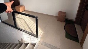 Eine Treppe führt zu einer Zwischenebene mit einer Holztür und einem kleinen braunen Hocker.