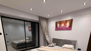 Ein modernes Schlafzimmer mit einem großen Bett, einer Schiebeglasdoor zum Balkon und einem Bild an der Wand.