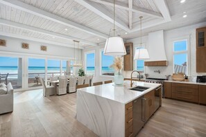 Una cucina moderna con un'isola grande, mobili in legno e vista sull'oceano.