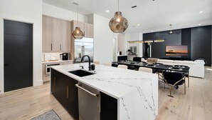A modern kitchen with a marble island, stainless steel appliances, and pendant lighting. - Isle Be Back|Private Pool|Waterfront|Golf Cart (Destin)