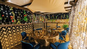 Ein Restaurant mit einem runden Tisch, blauen Stühlen und Lichterketten.