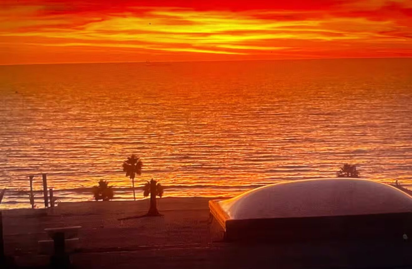 A beach scene with a sunset, palm trees, and a dome-shaped structure.