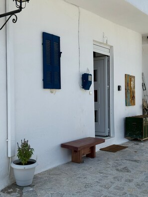 A white building with a wooden bench, a potted plant, and a door. - 3-bedroom villa in pleasant Kalo Chorio with AC and charm (Kalo Chorio)