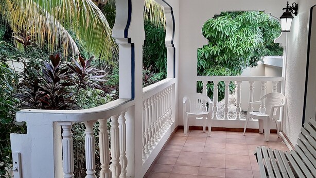 Ein Balkon mit weißen Geländern, einer Bank und zwei Stühlen.