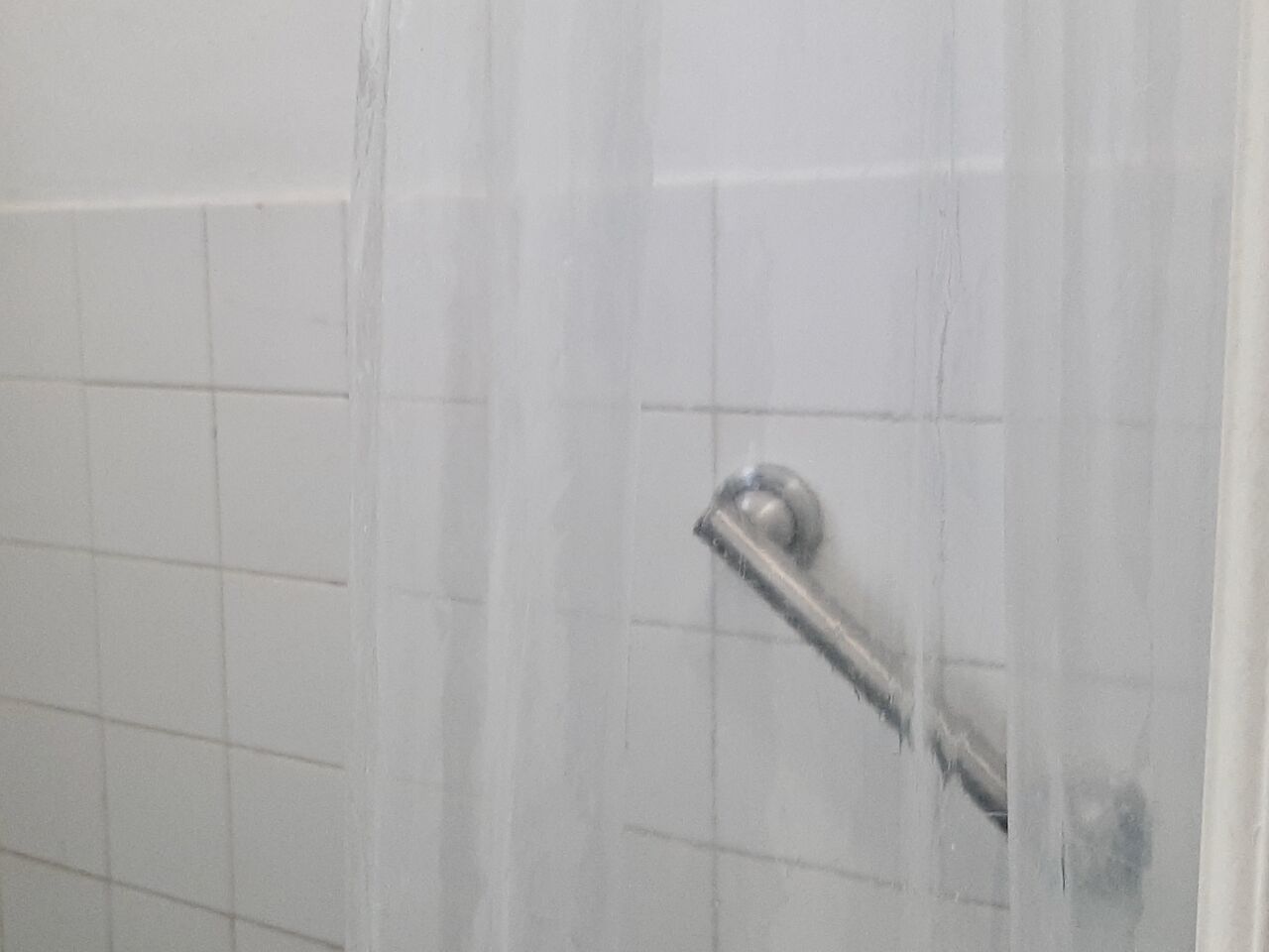 A shower with a metal handle and a glass door.