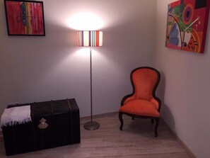 Et værelse med en sort kommode, en høj gulvlampe og en orange stol.