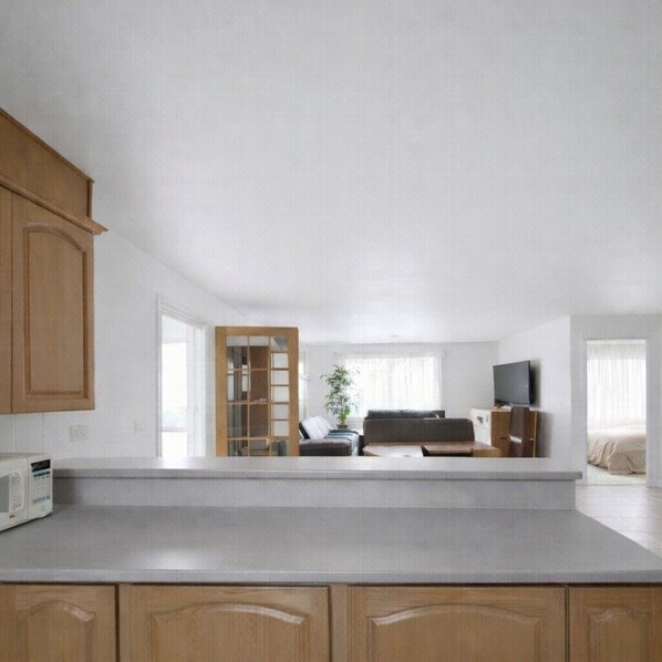 A modern kitchen with wooden cabinets, a built-in microwave, and a large window.