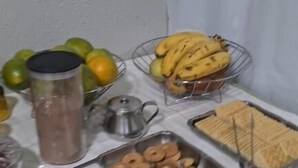 En buffet med forskellige spiser, herunder bananer, donuts og en beholder til drikkevarer.