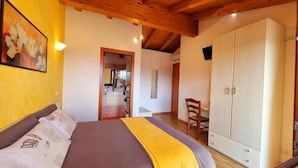 A bedroom with a bed, a wardrobe, a chair, and a painting on the wall. - VILLA VENEZIA (Mira)
