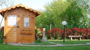 A wooden cabin with a pitched roof, a small porch, and a stone pedestal in front. - VILLA VENEZIA (Mira)