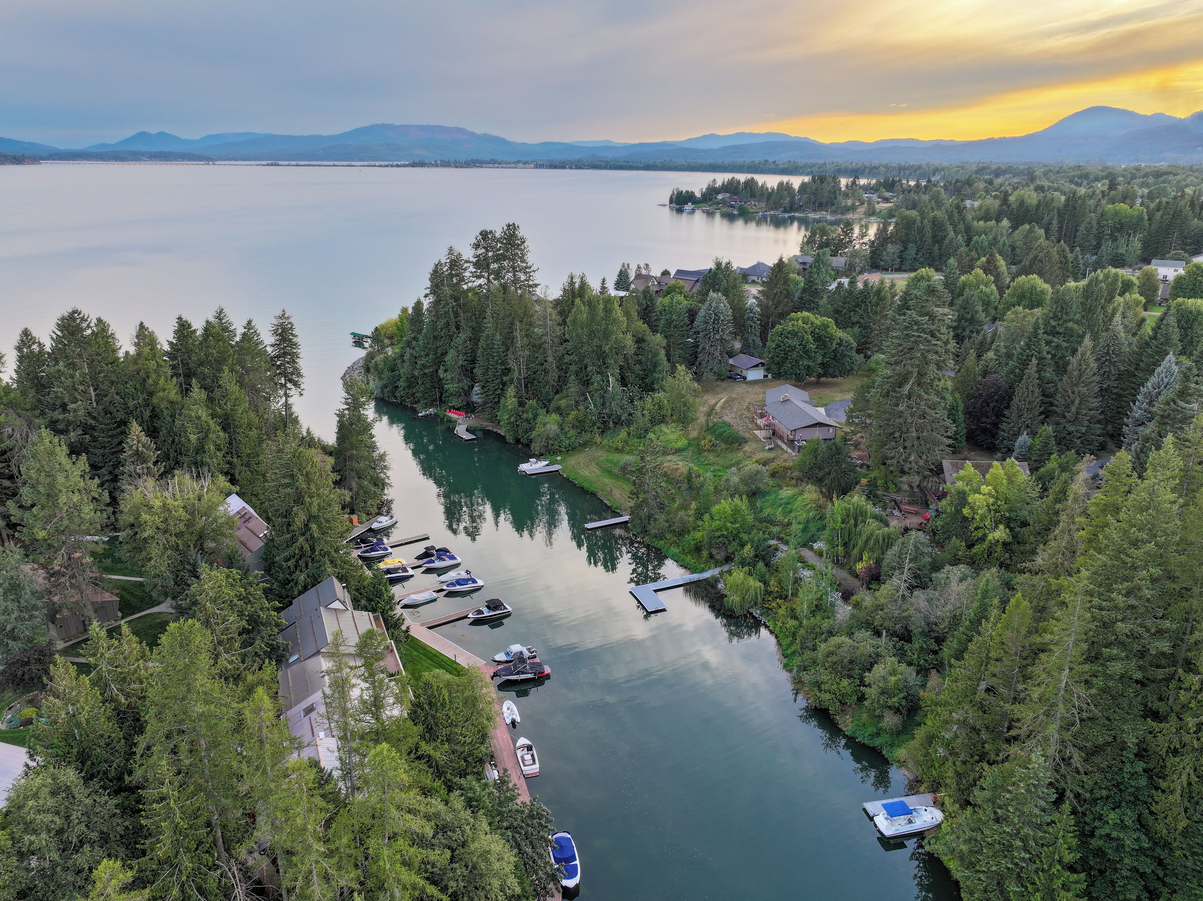 Une propriété au bord du lac, avec des bateaux amarrés, un port de plaisance et une zone boisée.