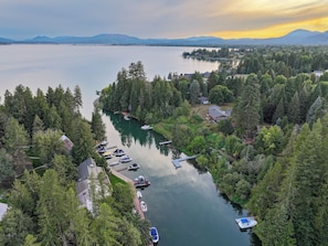 A lakeside property with docked boats, a marina, and a forested area. - Waterfront Retreat with Private Dock & Lake Views (Sandpoint)