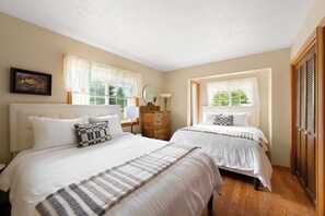 A hotel room with two beds, a wooden dresser, a mirror, and a window with curtains. - Waterfront Retreat with Private Dock & Lake Views (Sandpoint)