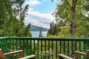 A deck with a table and chairs overlooking a lake with trees and mountains in the background. - Waterfront Retreat with Private Dock & Lake Views (Sandpoint)