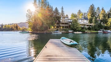 A wooden dock leading to a calm lake with boats, surrounded by multi-story buildings with balconies.