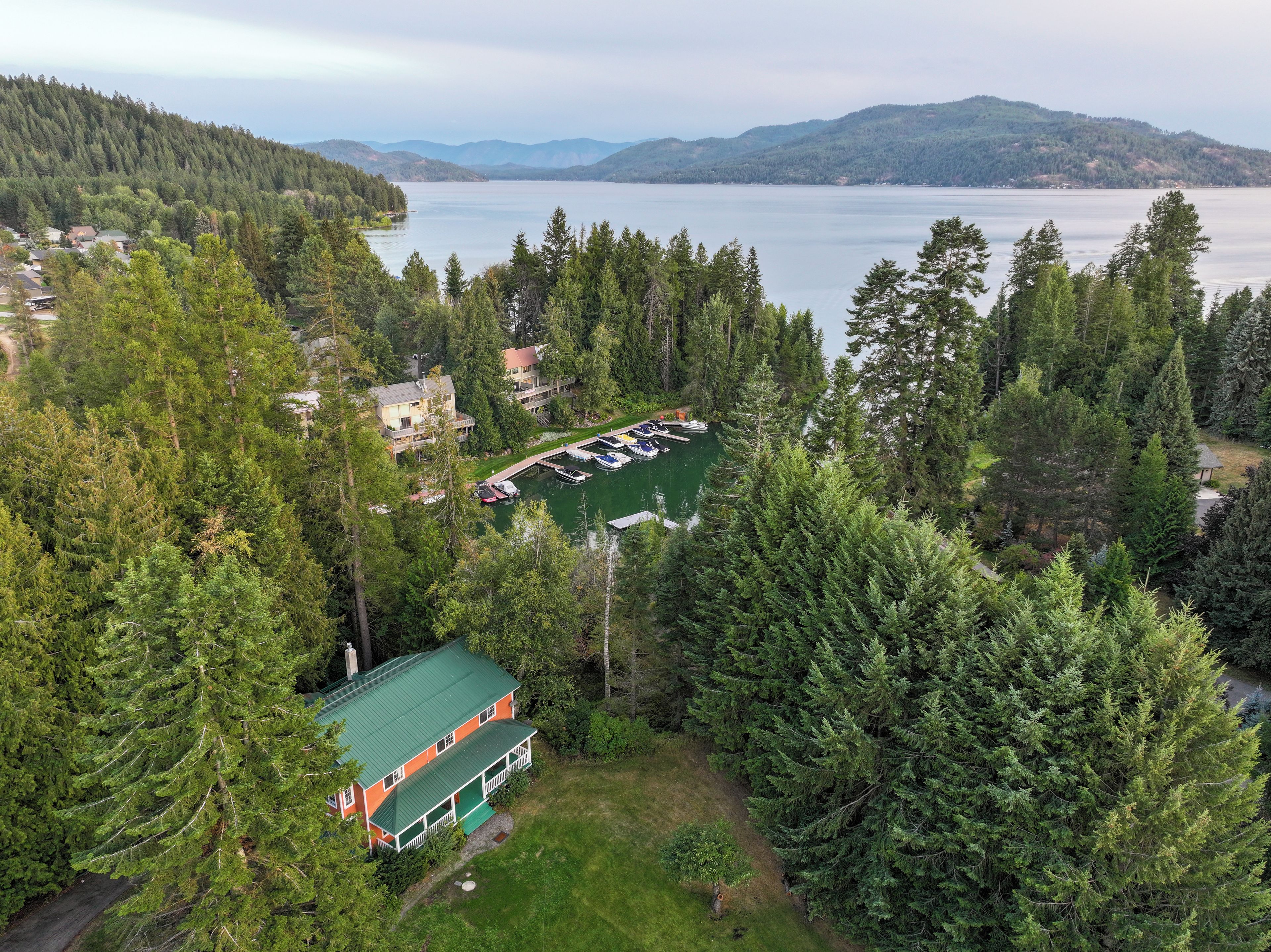 Une propriété au bord du lac, dotée d’un quai, d’une maison avec un toit végétalisé et, en arrière-plan, de collines densément boisées.