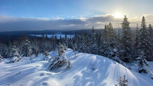 A snowy landscape with a clear sky and the sun shining through the clouds.