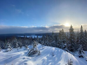 A snowy landscape with a clear sky and the sun shining through the clouds.