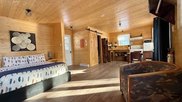 Un interior de madera con una cama, un sofá y una zona de cocina.