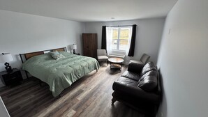 A bedroom with a bed, a sofa, a chair, a small table, and a window. - Room-red Farm Inn - Room 12 (Howie Centre)