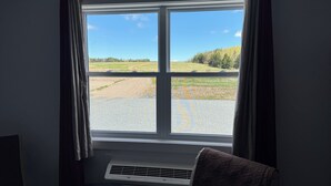 A room with a large window, a bed, a chair, and an air conditioning unit. - Room-red Farm Inn - Room 12 (Howie Centre)