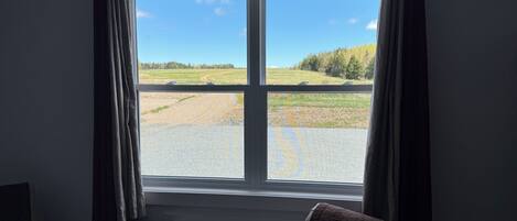 A room with a large window, a bed, a chair, and an air conditioning unit.