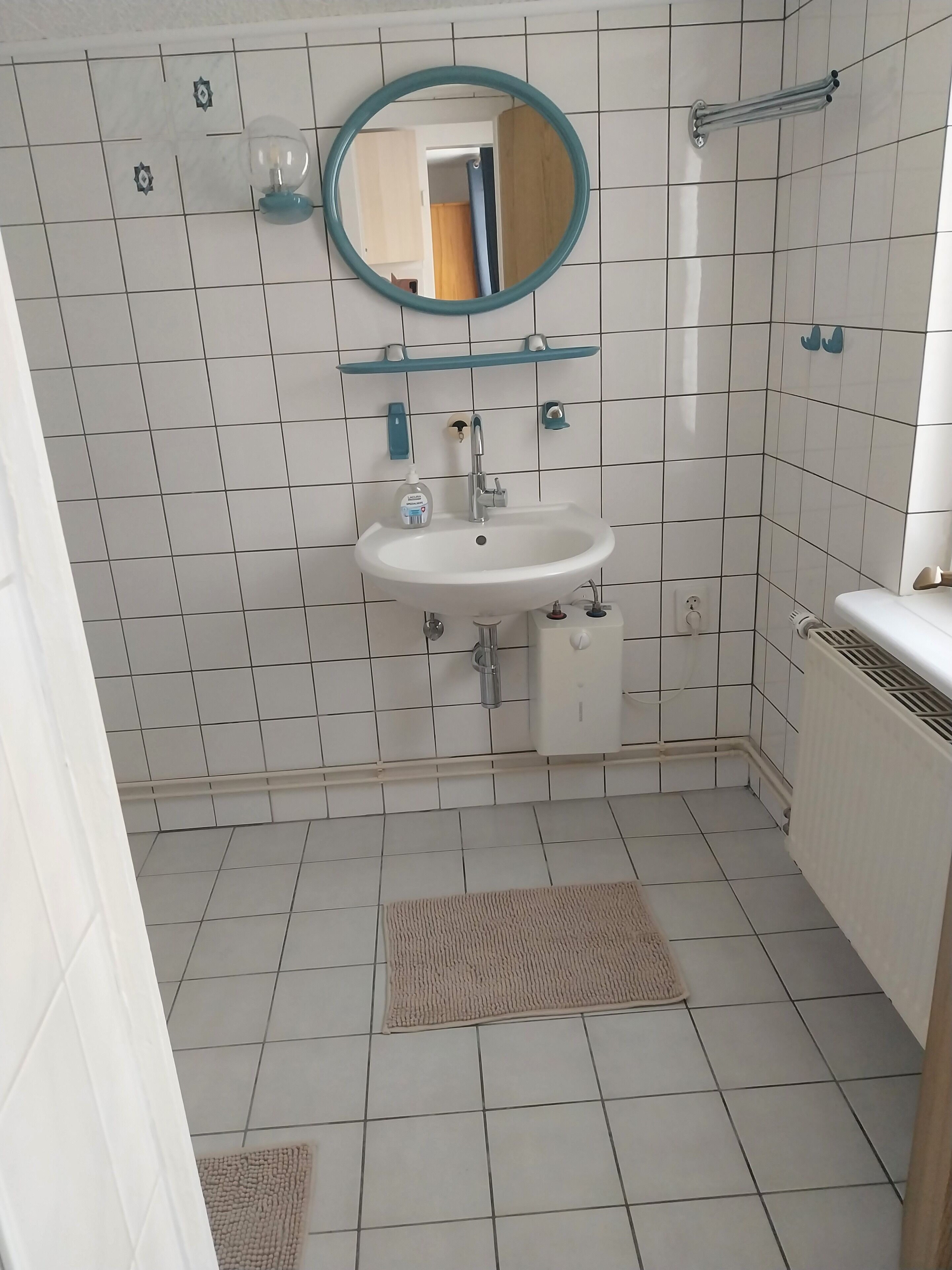 Un bagno con un lavandino bianco, uno specchio e un porta asciugamani.