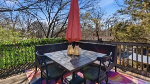 An outdoor patio with a table and chairs, surrounded by greenery and trees. - The GOAT - Pool, Hot Tub, Gym, Sauna & Gameroom (Belmont)