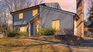 A two-story house with a prominent chimney, a front porch, and a well-maintained lawn. - The GOAT - Pool, Hot Tub, Gym, Sauna & Gameroom (Belmont)