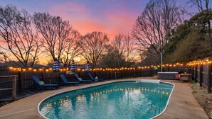 A backyard with a swimming pool, lounge chairs, and string lights. - The GOAT - Pool, Hot Tub, Gym, Sauna & Gameroom (Belmont)