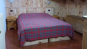 Une pièce en bois avec un lit, un banc en bois et une petite table.