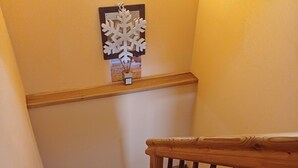 Un escalier en bois avec une rampe, un plancher en bois et un flocon de neige décoratif fixé au mur.