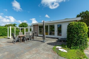 Une maison moderne dotée d’un patio, d’un coin repas et d’une véranda.