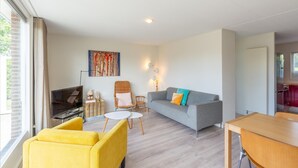En moderne stue med en grå sofa, en gul lænestol og et spisebord.