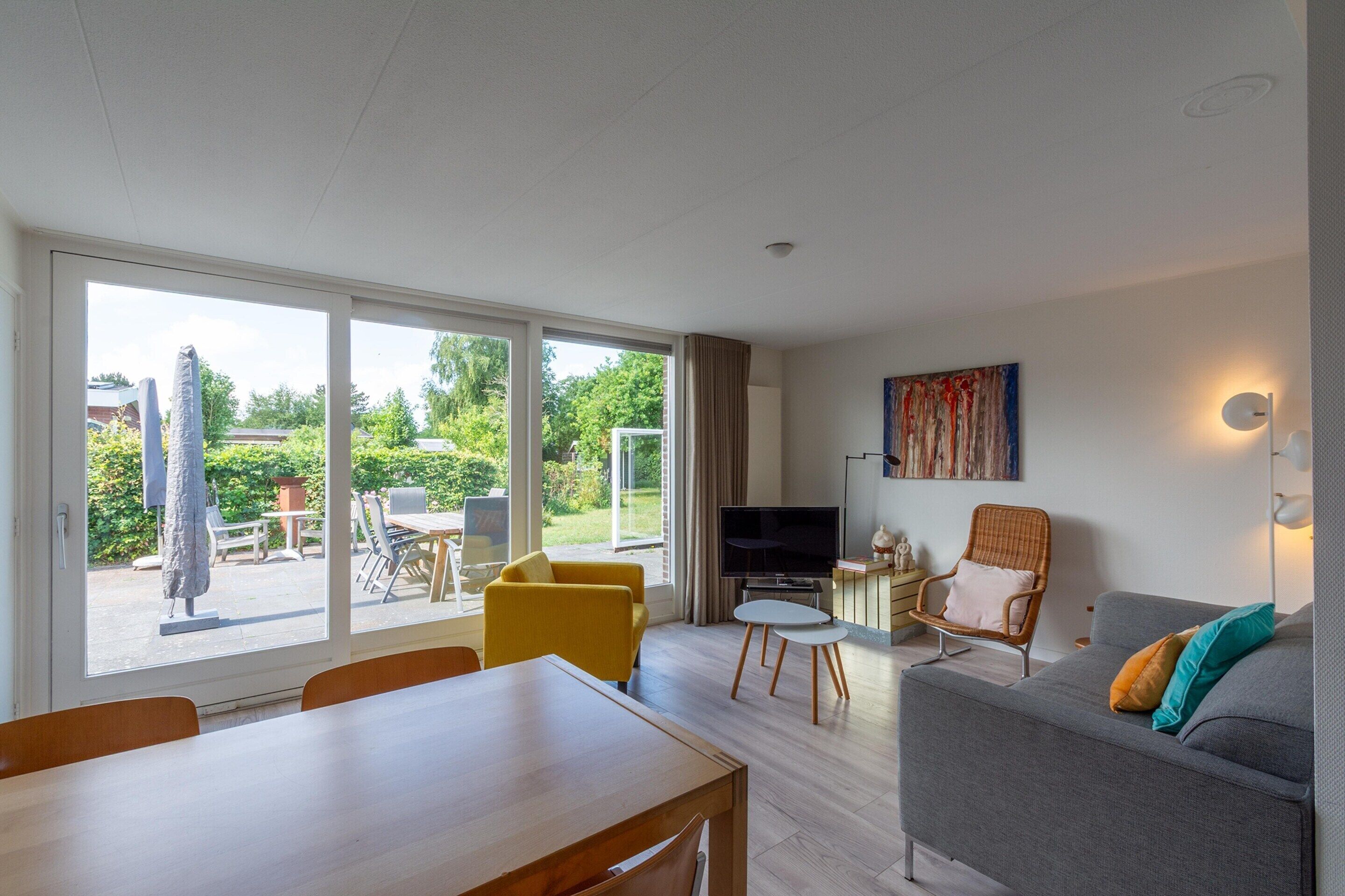 A modern living room with a sofa, a dining table, and a TV.