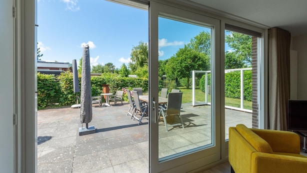 Et værelse med en skydedør, der fører ud til en udendørs terrasse.