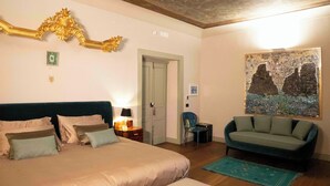 A bedroom with a large bed, a sofa, a painting, and a wooden ceiling. - Palazzo Carafa Santangelo - historic residence of the 400'in the heart of the ancient city (Napoli)