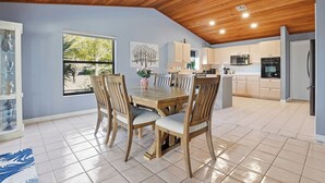 A spacious kitchen with wooden cabinets, a dining area with a wooden table and chairs, and a ceiling fan. - Spacious 3BR Heated Pool Home-Pets OK-12 min to beach (Cape Coral)